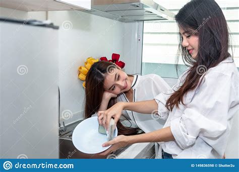 Two Asian Women Washing Dishes Together In Kitchen People