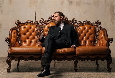 Солидный мужчина в костюме сидит на диване обои для рабочего стола