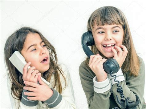 two seven year old girls talking on the old vintage phones with — stock