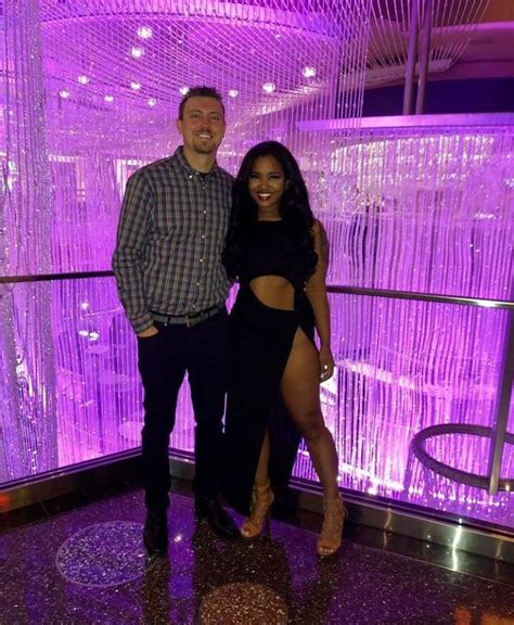 A Man And Woman Posing For A Photo In Front Of A Purple Wall With Lights