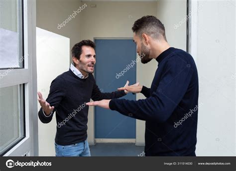 young men standing door entrance quarreling   stock photo