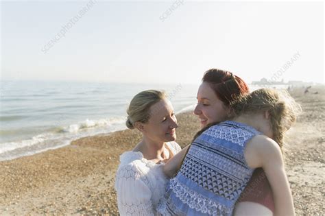 Lesbian Couple Hugging Daughter On Beach Stock Image F023 0066