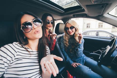 group of girls having fun in the car and taking selfies