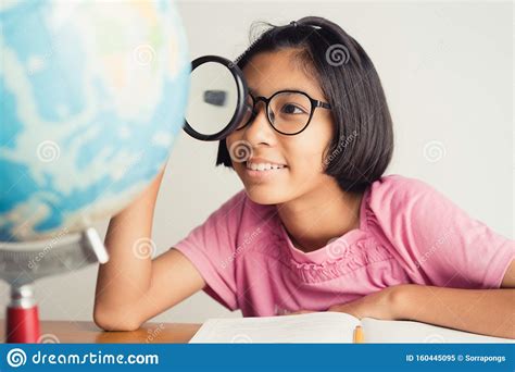 asian girl wearing glasses is smiling and using a magnifying glass in