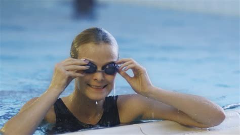 professional concentrated female swimmer in goggles on starting block before jump into water