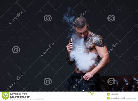 Vaper The Man With A Muscular Naked Torso With Tattoos