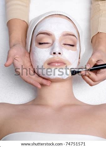 cosmetician applying facial mask   face  young beautiful woman