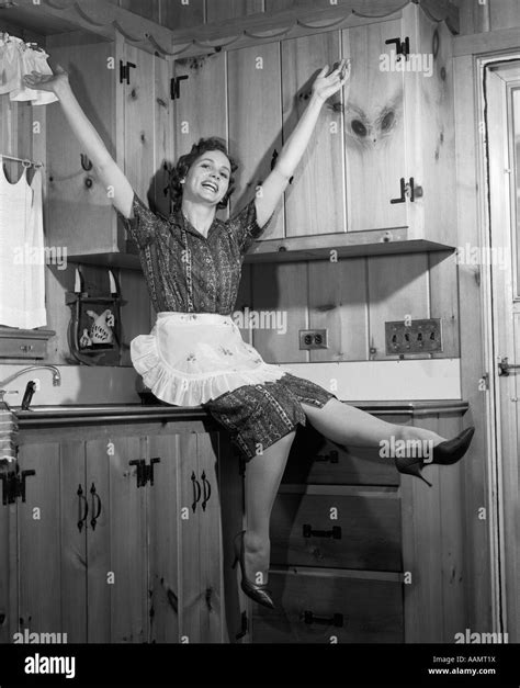 1950er Jahre Hausfrau Sitzen Auf Arbeitsplatte Treten FÜße Arme In Die