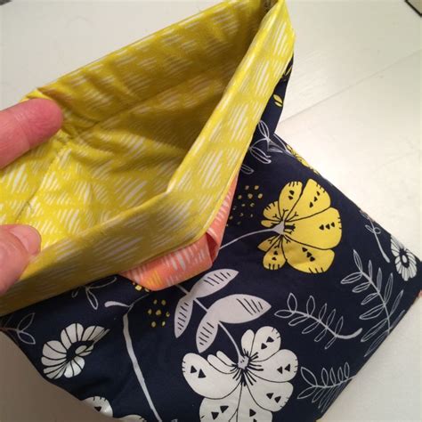 person  holding  yellow  blue flowered pouch   white countertop