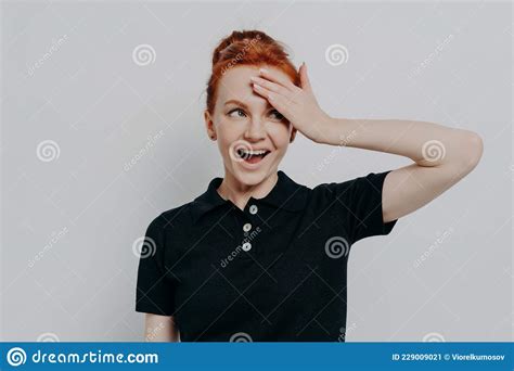 Happy Young Redhead Woman With Opened Mouth Touching Her Forehead With