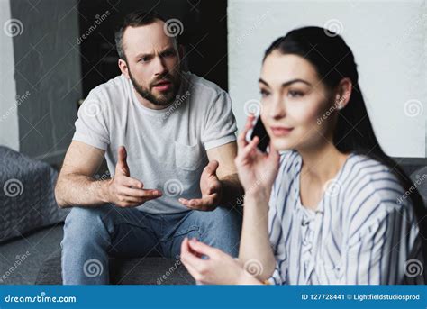 Angry Man Talking To His Wife While She Talking By Phone Stock Image
