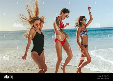 Happy Women On Vacation Sunbathing And Enjoying At Beach With Sea In