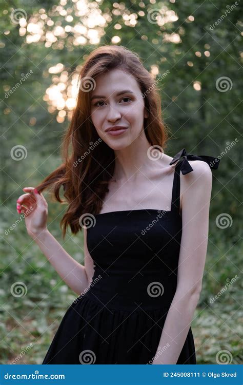 Attractive Young Brunette Woman In A Black Dress Posing In The Forest
