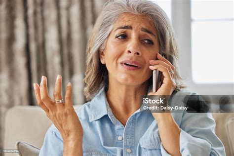 Frustrated Mature Woman Receiving Unwanted Telephone Call At Home Stock