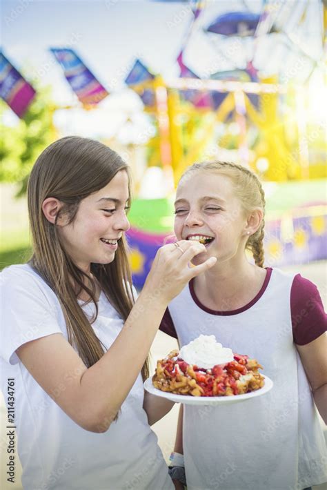 foto stock two laughing and smiling teenage girls eating a funnel cake