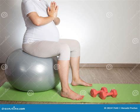 a pregnant girl with a big belly does yoga on a mat sports and