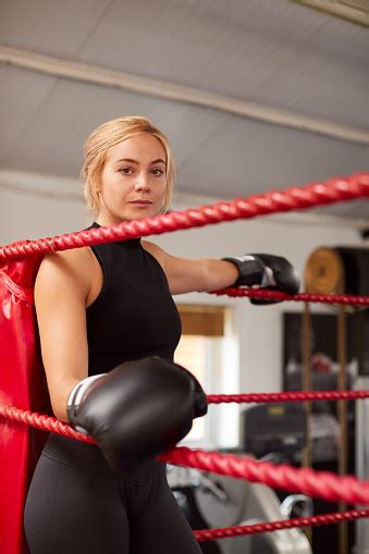 Portrait Of Female Boxer In Gym Wearing Boxing Gloves Standing In