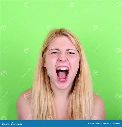 Portrait Of Desperate Blond Young Woman Screaming Against Green Stock