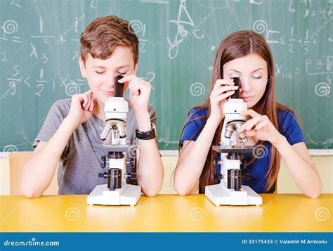 student im klassenzimmer unter verwendung eines mikroskops stockbild