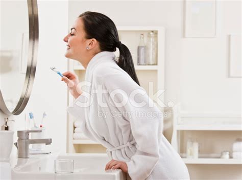 woman holding toothbrush and looking in mirror stock