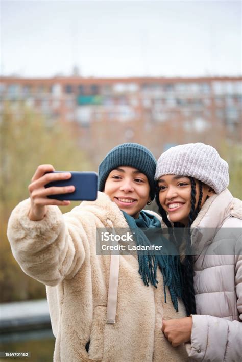 Happy Dominican Lesbian Couple Taking A Selfie With Phone At Street In