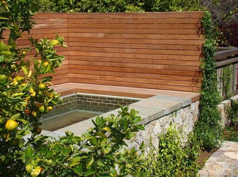 An Outdoor Hot Tub Surrounded By Greenery And Stone Walls In A Garden