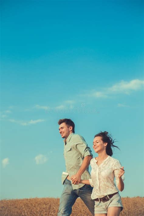 Young Couple In Love Outdoor Couple Runs Across The Field Stock Image