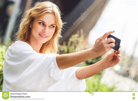 portret van glimlachende jonge vrouw die selfie foto in