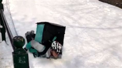 video deliveroo driver slides down ice belly first with food order