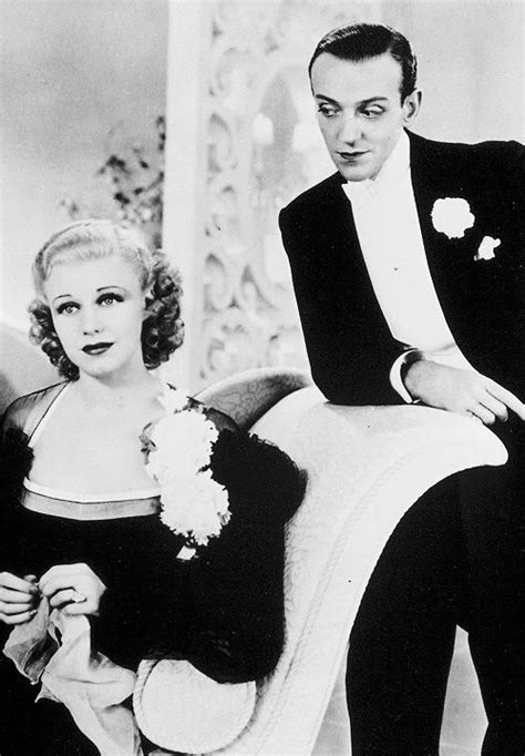 A Man In A Tuxedo Standing Next To A Woman Sitting On A Chair