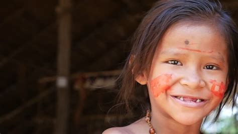 cute native brazilian girl looking to the camera at an indigenous tribe in the amazon stock
