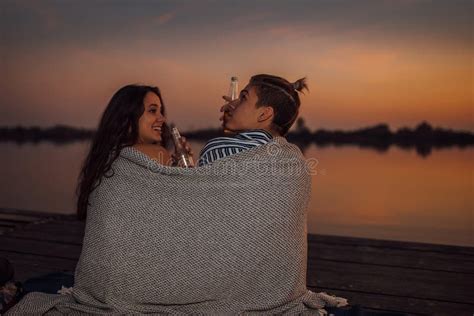 Young Couple Having A Romantic Date By The River During Sunset Covered