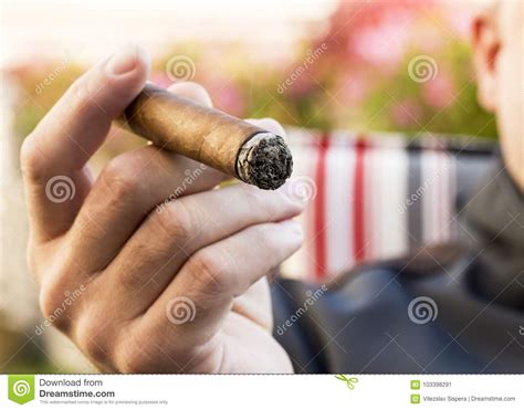 detail van de hand van een rokende mens die een brandende sigaar houden met stock afbeelding