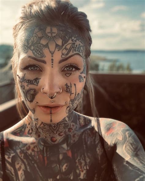 A Woman With Tattoos And Piercings On Her Face