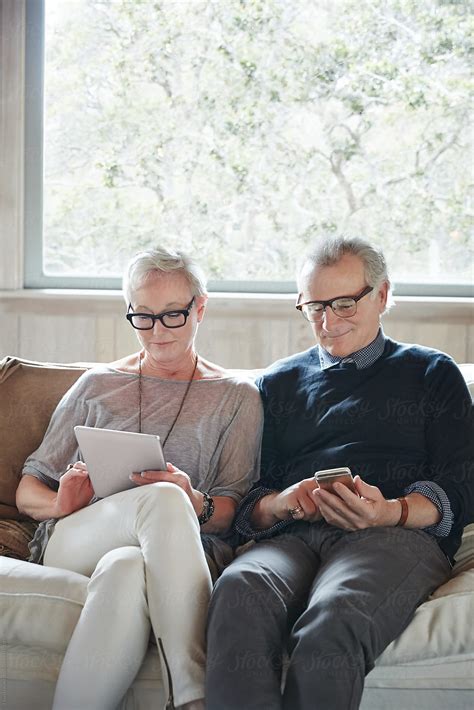Mature Couple With Grey Hair Looking At Digital Tablet And Phone At