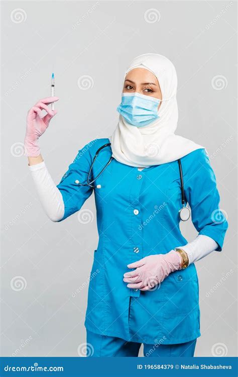 Muslim Doctor Or Nurse In Hijab And Medical Face Mask Holding A Syringe