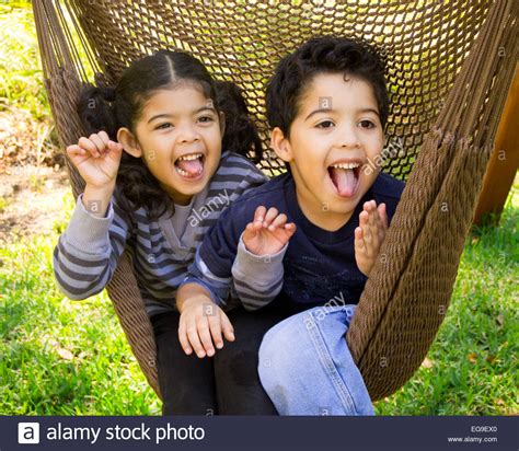 twin brother and sister sitting in a hammock pulling funny