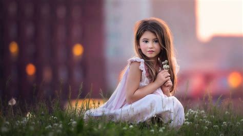 cute baby girl  sitting  green grass  flowers  hand wearing pink dress posing
