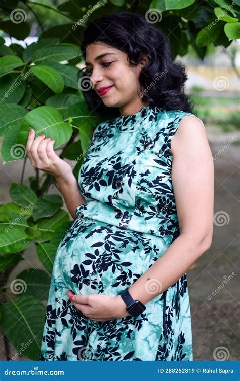 a pregnant indian lady poses for outdoor pregnancy shoot and hands on