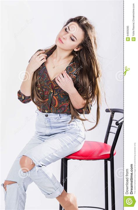beautiful girl in shirt sitting on a high chair against a white