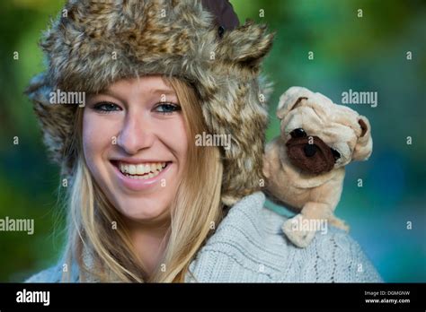 Young Woman Wearing A Fur Hat With A Plush Pug On Her Shoulder Stock