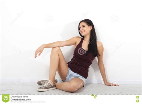 beautiful brunette asian caucasian fitness model sitting on floor near white wall in an empty