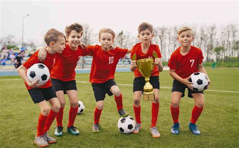 happy junior sports team young boys  soccer team holding golden cup  soccer balls group