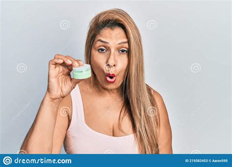 Middle Age Hispanic Woman Holding Cosmetic Moisturizer Facial Cream