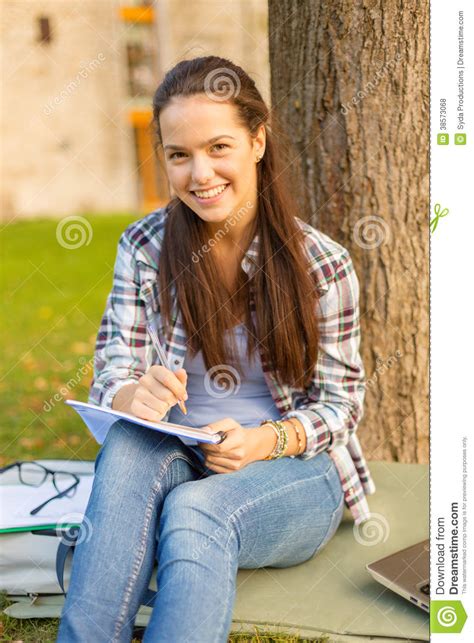 glimlachende tiener die in notitieboekje schrijven stock