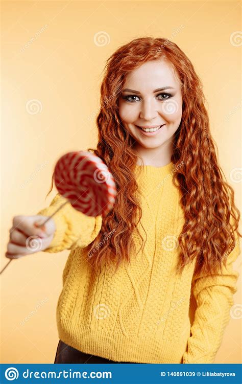 Beautiful Curly Redhead Woman Holding A Red White Lollipop