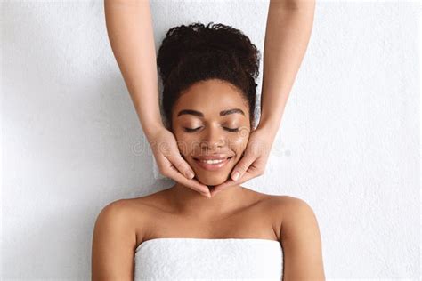 therapist making lifting facial massage  beautiful black lady stock