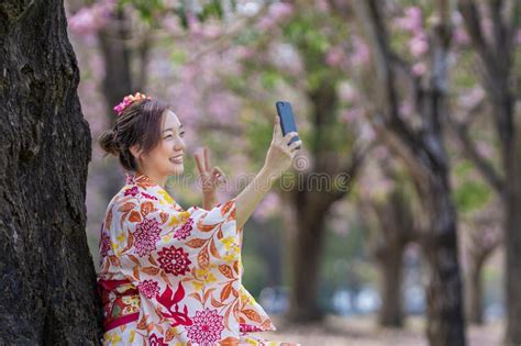 Japanese Woman In Traditional Kimono Taking Selfie With Peace Gesture