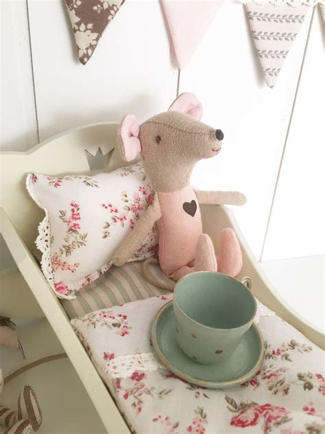 stuffed mouse sitting  top   bed    cup  saucer