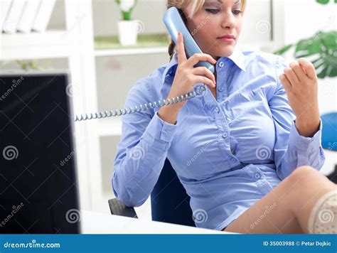 sexy sekretär der im büro sitzt und am telefon spricht stockfoto